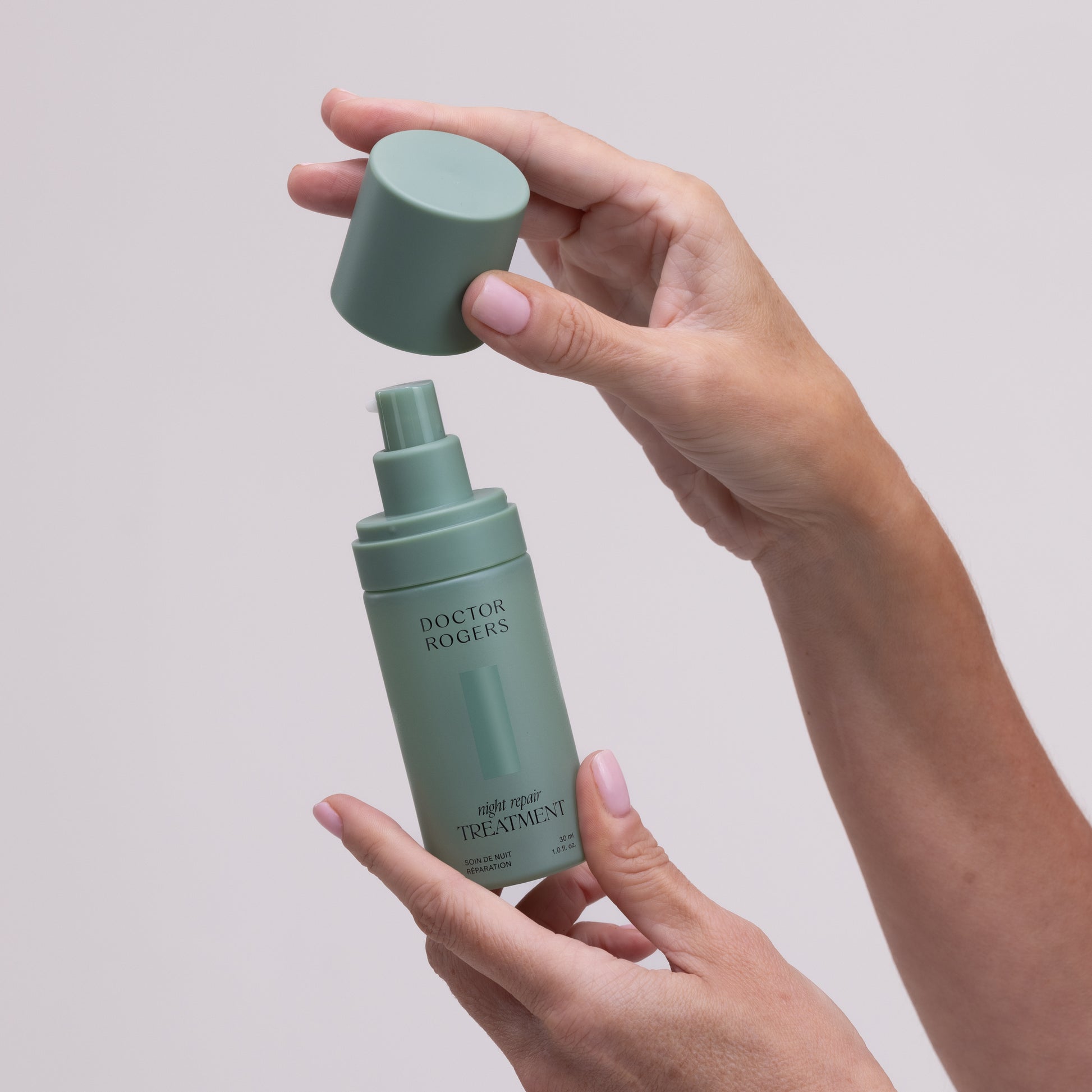 Person pulling lid of best retinol alternative for sensitive, mature skin Doctor Rogers Night Repair Treatment off of dark green, eco-friendly, sustainable 30ml packaging bottle to display displenser pump