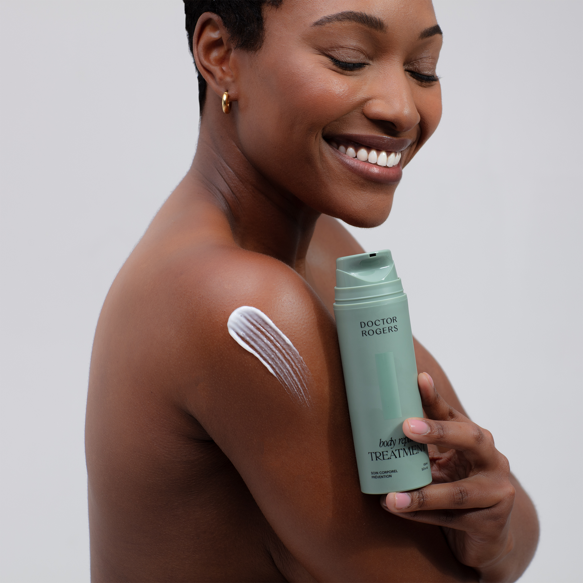 Doctor Rogers Body Duo | Featuring the Body Repair Treatment to smooth crepey skin, soften wrinkles, and even tone. Also includes Body Cream to deeply hydrate and strengthens the skin barrier using the highest-quality humectants, emollients, and ceramides.  
Picture featuring women holding green 5oz eco friendly tube of Body Repair Treatment with product smudge on shoulder. 
Safe for men and women wtih all skin types including sensitive, mature, aging skin.