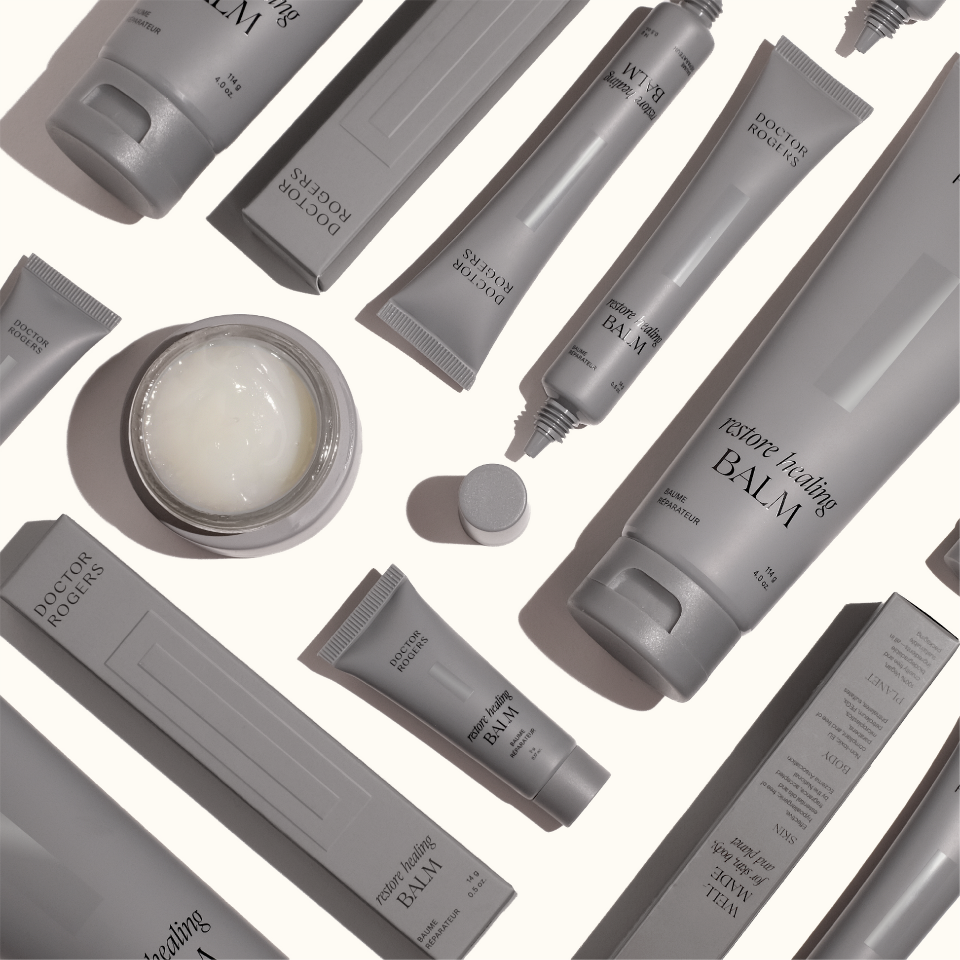 Various recyclable grey packages of Doctor Rogers Restore Healing Balm including the 0.5oz tube, 5 gram tube, 4 oz tube, and open 1oz jar all made with castor oil to quickly heal skin with a hypoallergenic healing ointment